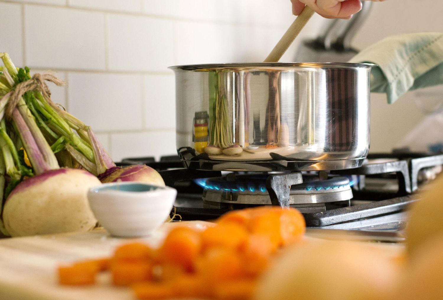 A pot on a stove surrounded by vegetables